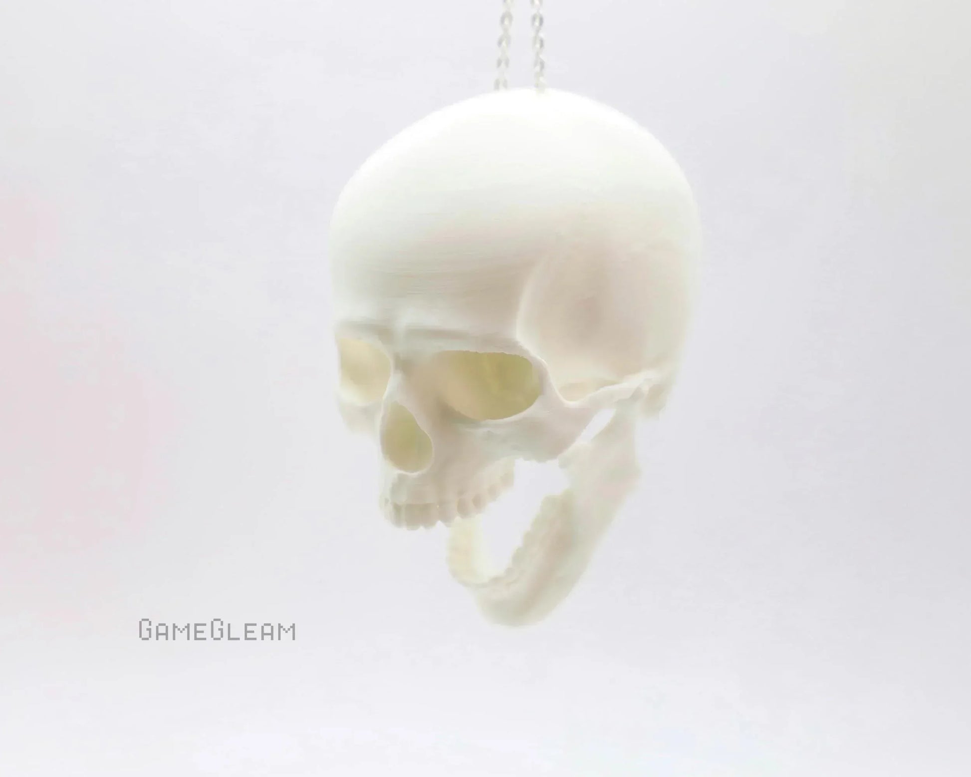 White hanging skull car charm with open jaw on minimalist white background