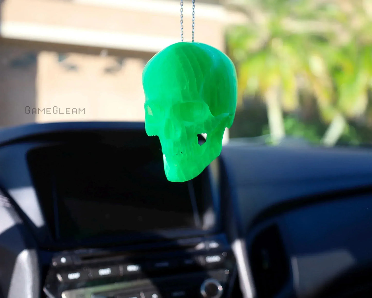Green translucent skull car charm hanging from rearview mirror in vehicle interior