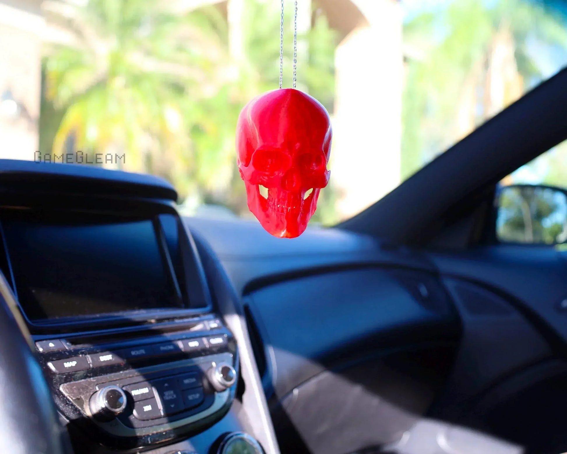 Handmade red skull car dice charm hanging on rearview mirror inside a car