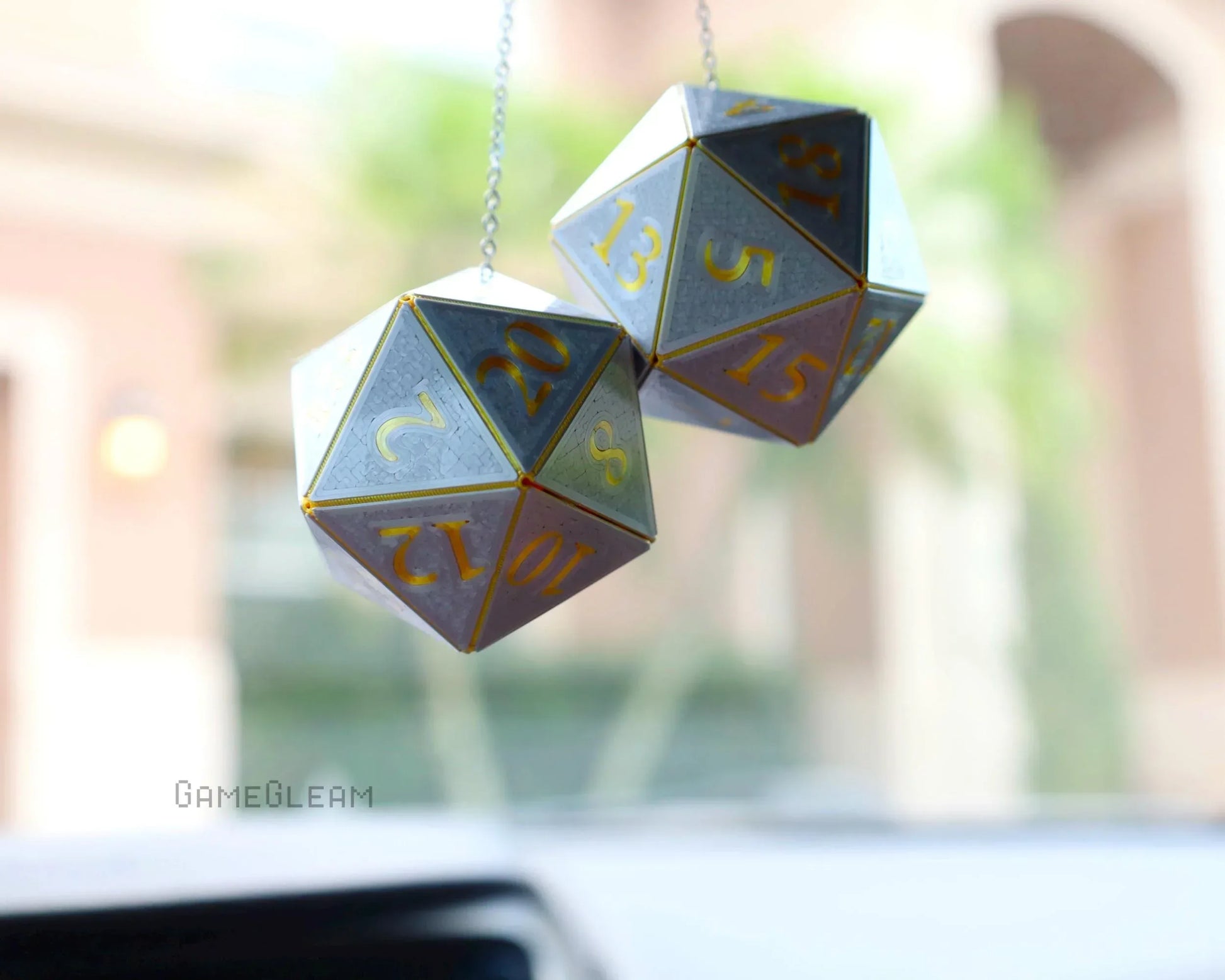 Holographic twenty-sided dice car hanging charm with gold numbers, photographed inside a car.