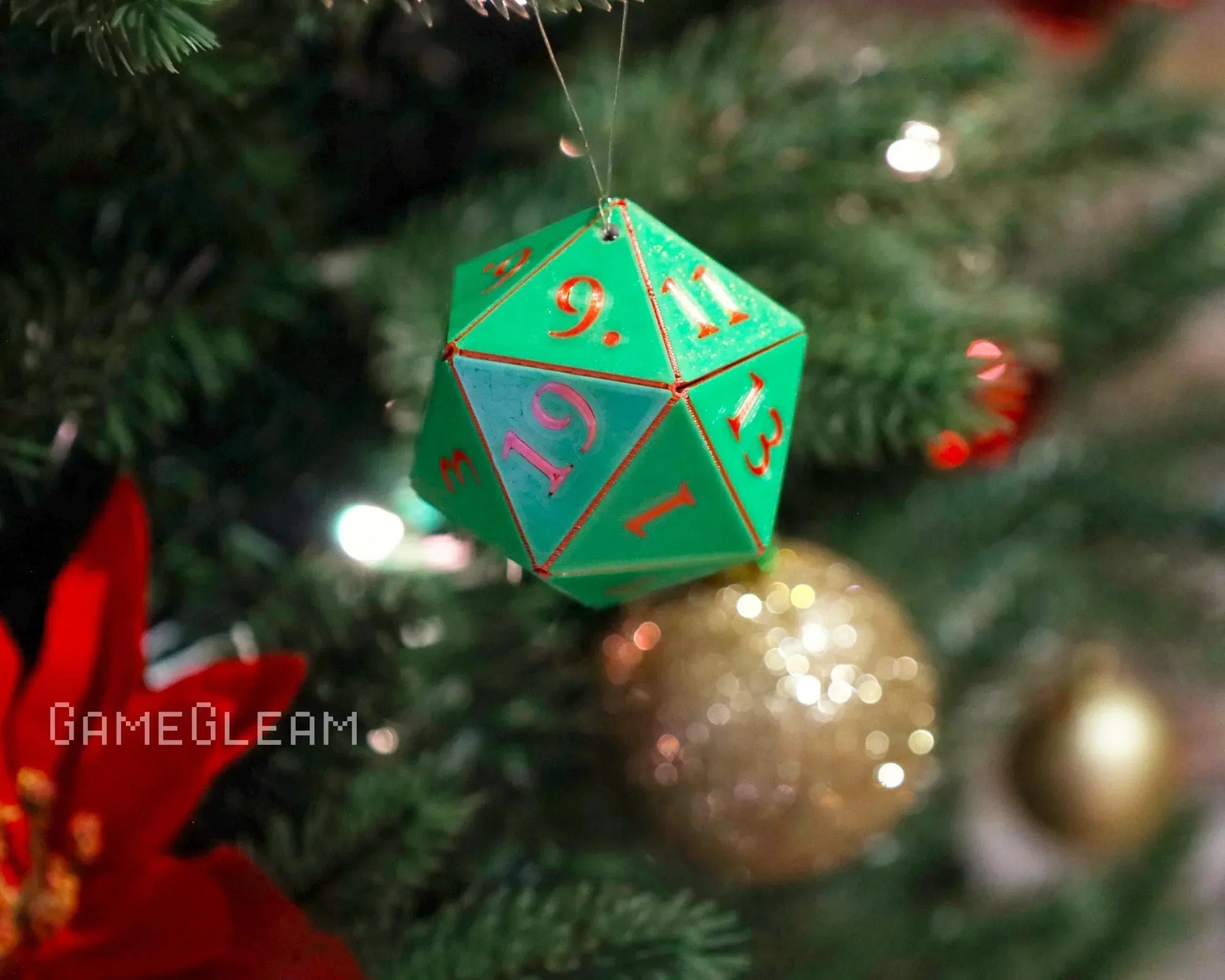 Green 20-sided dice ornament with red numbers hanging on a decorated Christmas tree.