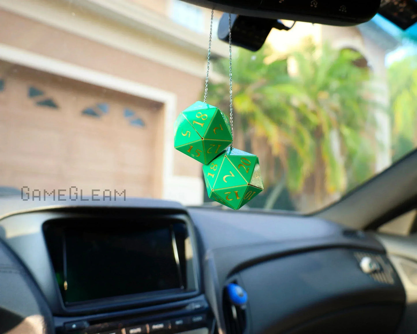 Green 20-sided dice car charm hanging from rearview mirror in parked vehicle