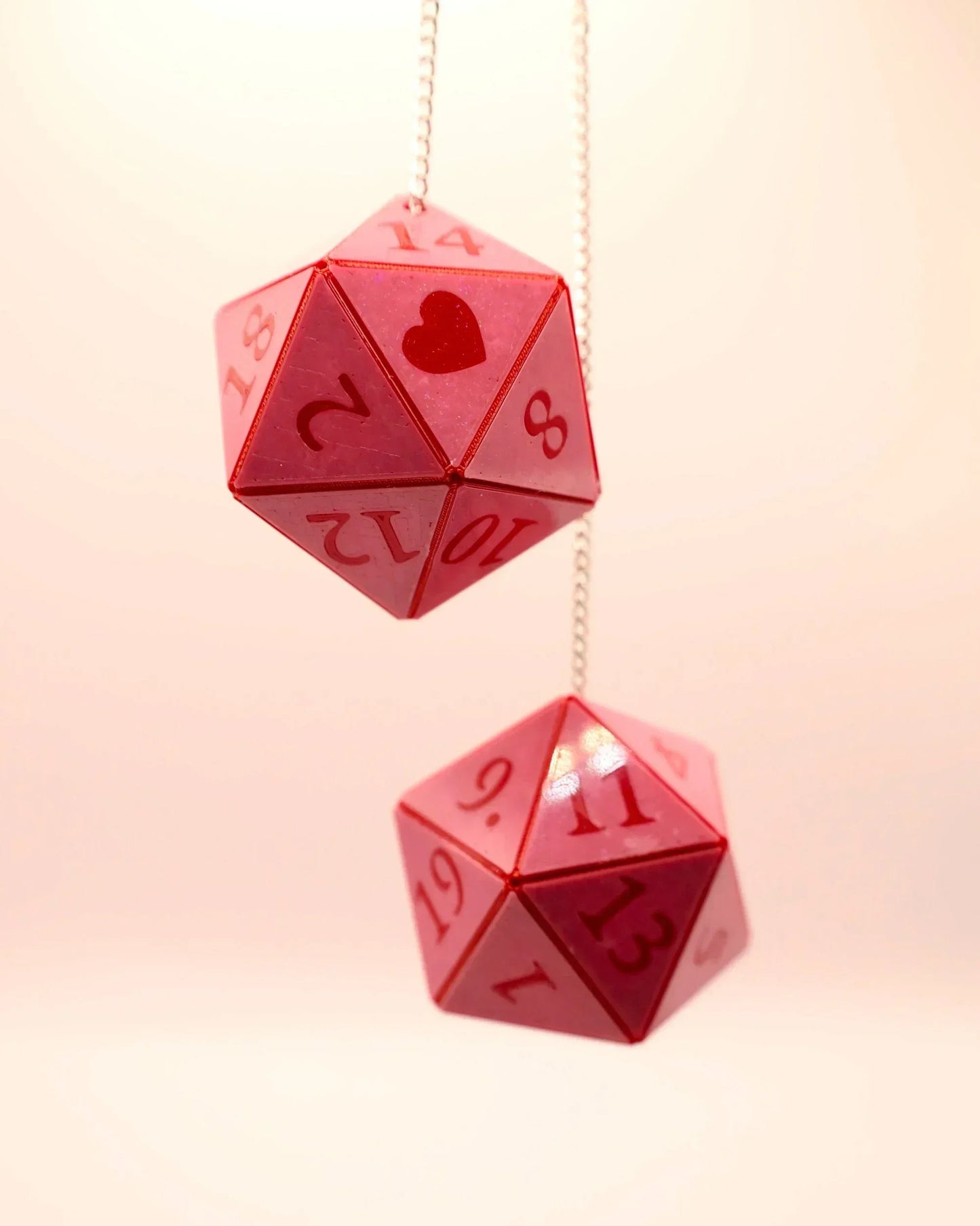 Pink handmade 20-sided dice car charm with red numbers and heart accent, hanging on chain