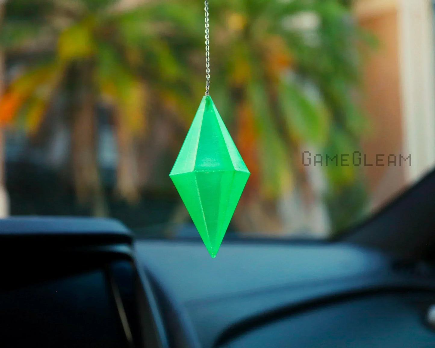 Green geometric car charm hanging from rearview mirror in vehicle interior