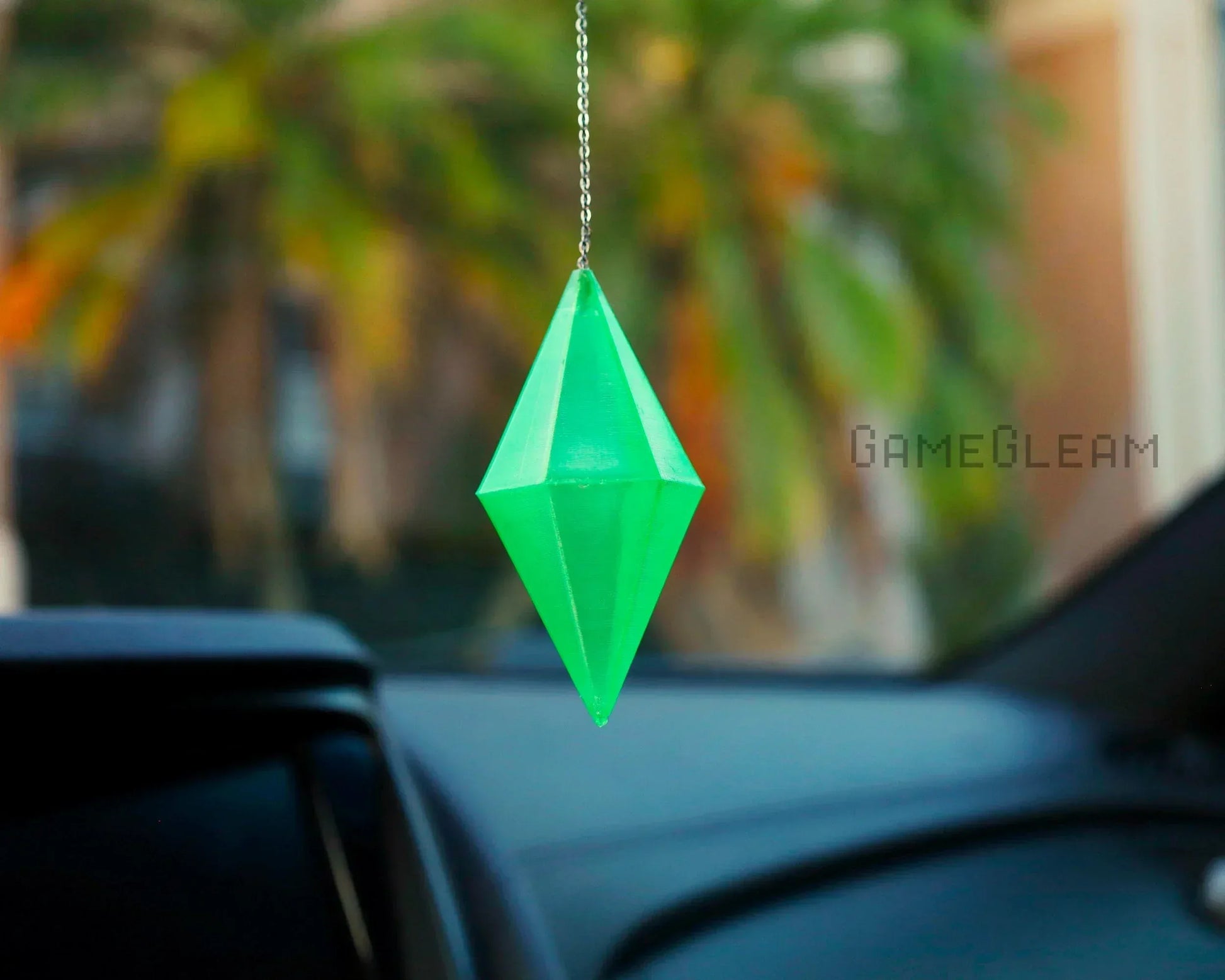 Green geometric car charm hanging from rearview mirror in vehicle interior