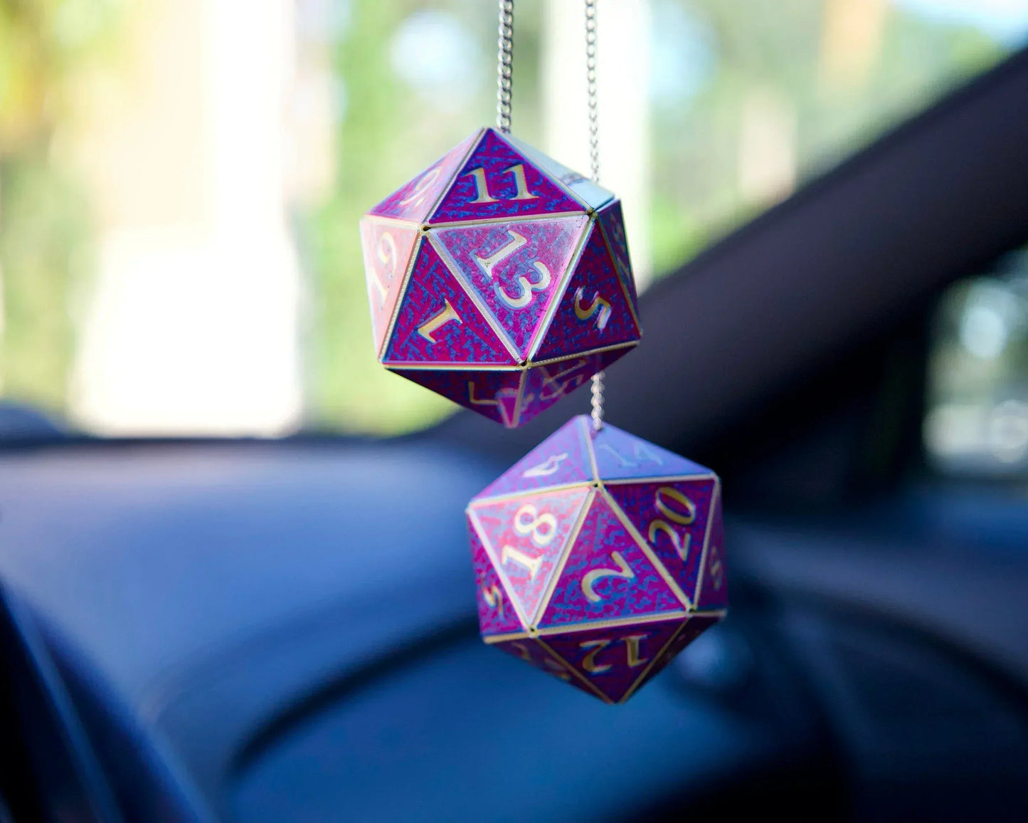 Holographic purple D20 dice car charm hanging from rearview mirror in a vehicle.