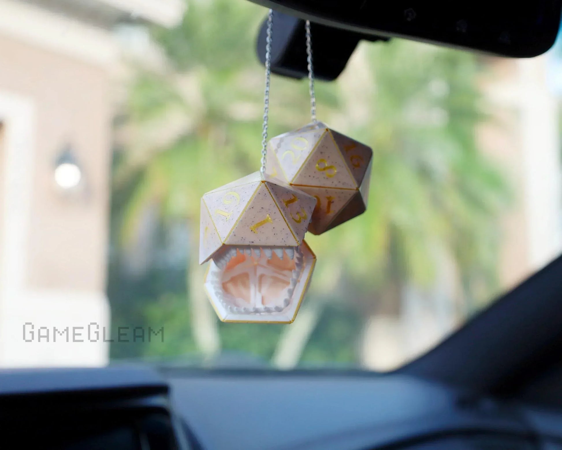 Handmade oversized polyhedral dice car charm with open mouth design, hanging from rearview mirror.