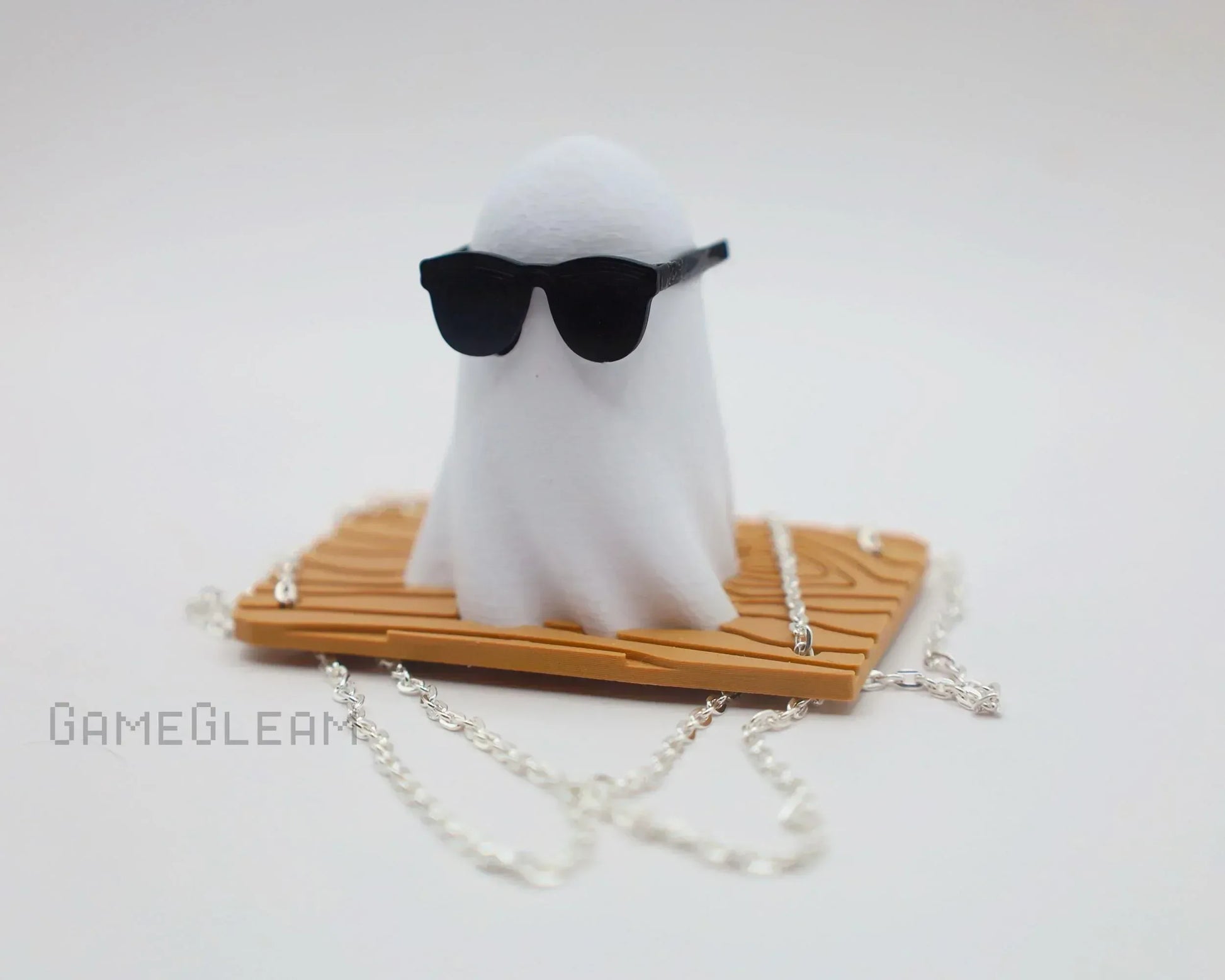 Handmade ghost figurine with black sunglasses on wood-texture base, silver chain accessory