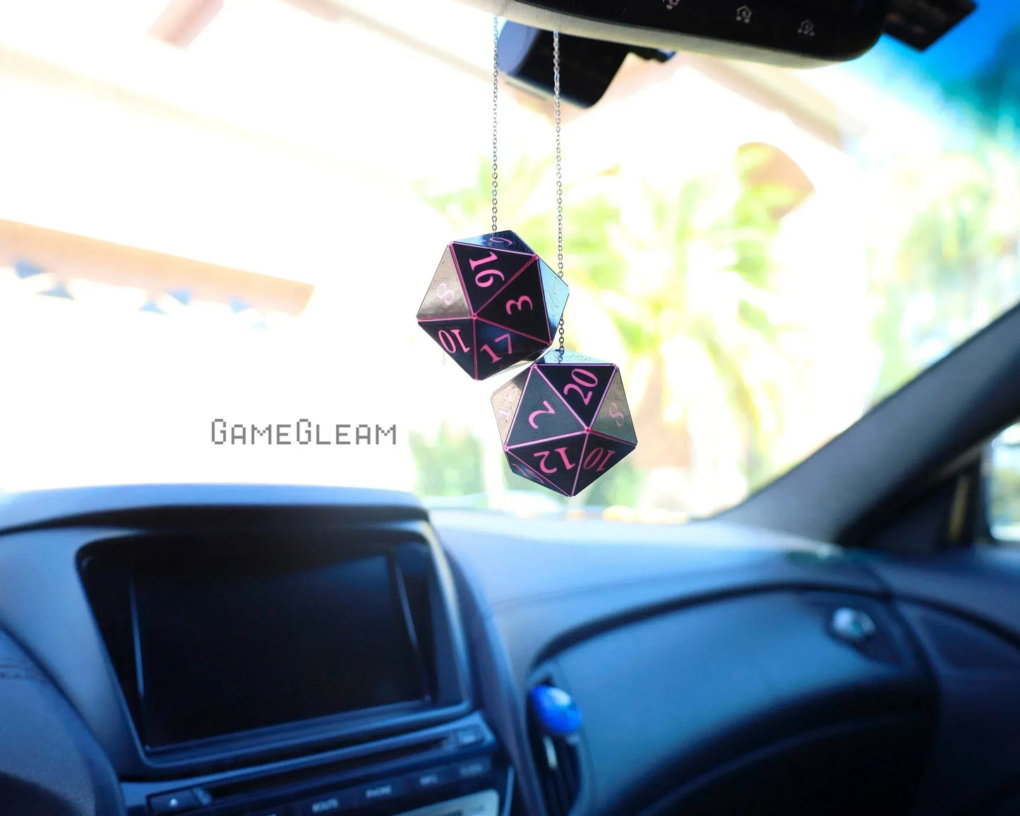 Pair of black and pink twenty-sided dice hanging as car charms from rearview mirror