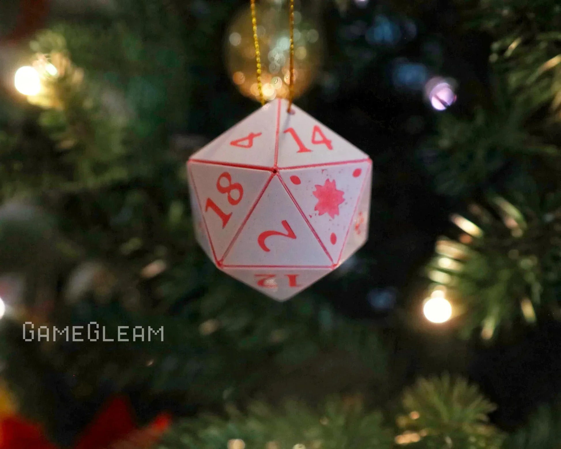 Handmade twenty-sided dice ornament with red numbers hanging on a Christmas tree