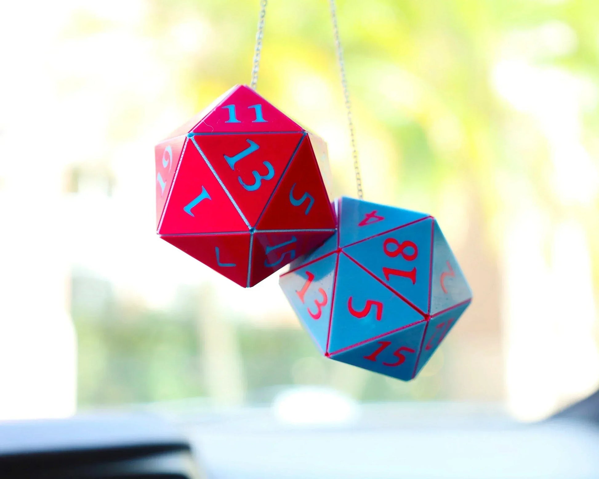 Holographic red and blue twenty-sided dice hanging from car rearview mirror charm