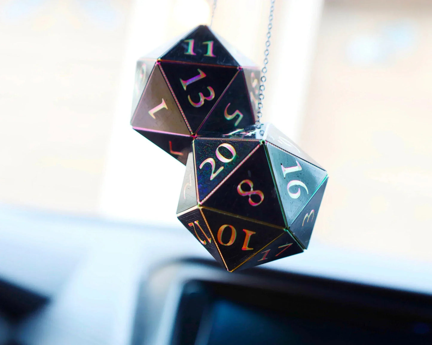 Holographic black twenty-sided dice car charm hanging in a vehicle interior