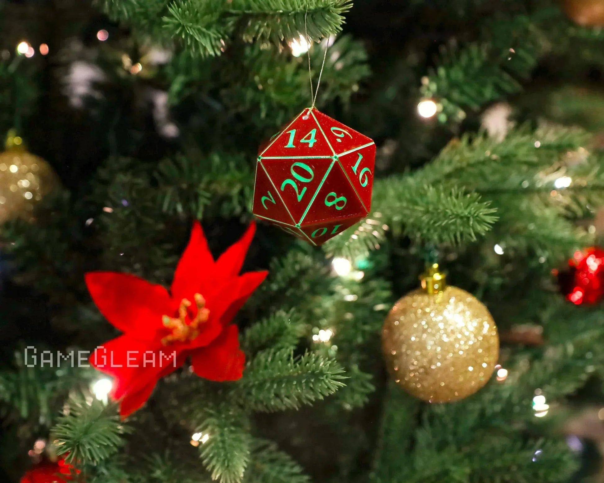 Red twenty-sided dice ornament hanging on a Christmas tree with gold bauble and red flower