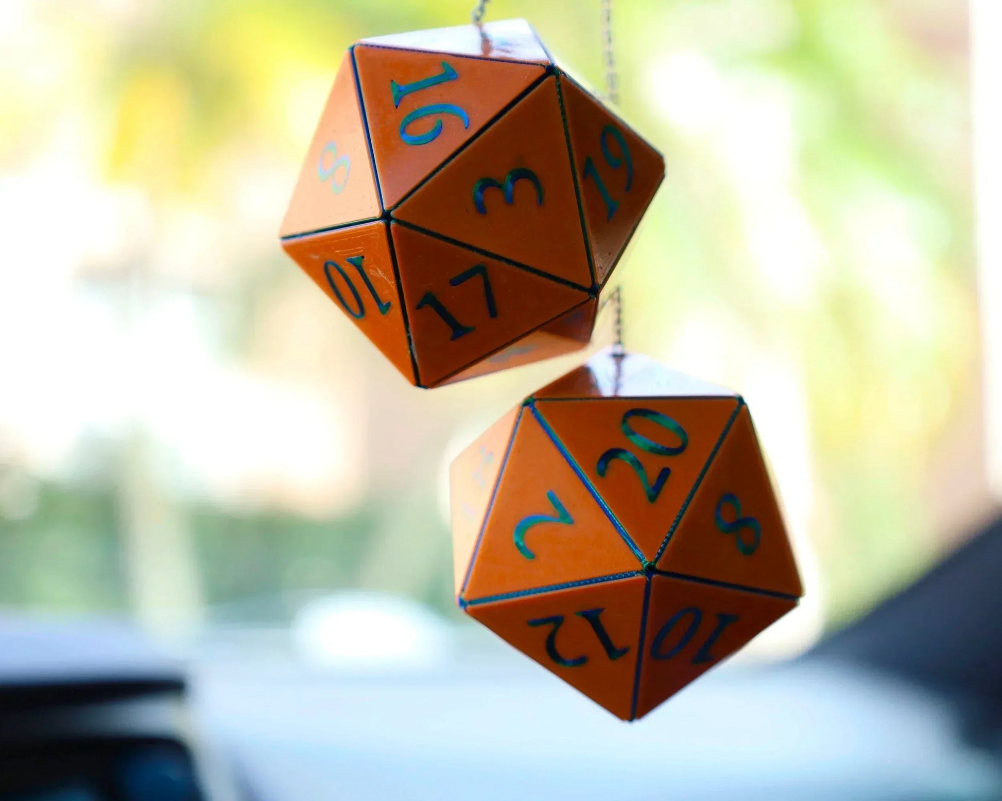 Orange twenty-sided dice hanging as car rearview mirror charms, perfect for tabletop RPG fans.