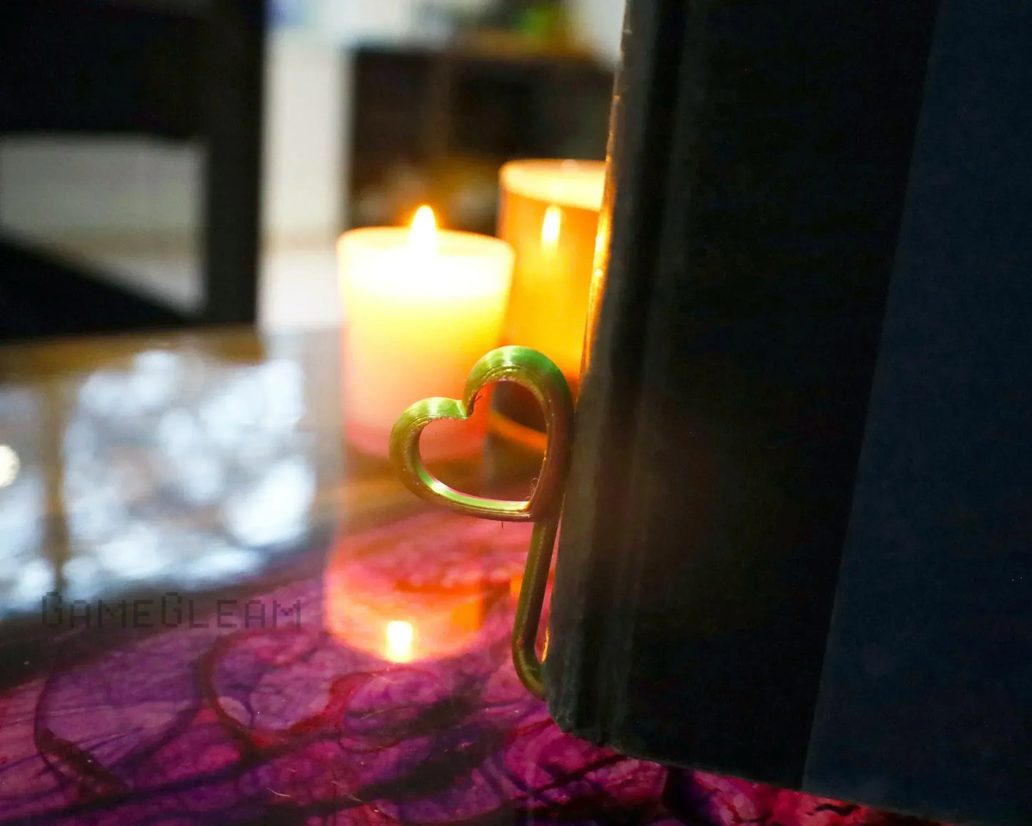 Metal heart-shaped bookmark in book with glowing candles in cozy background