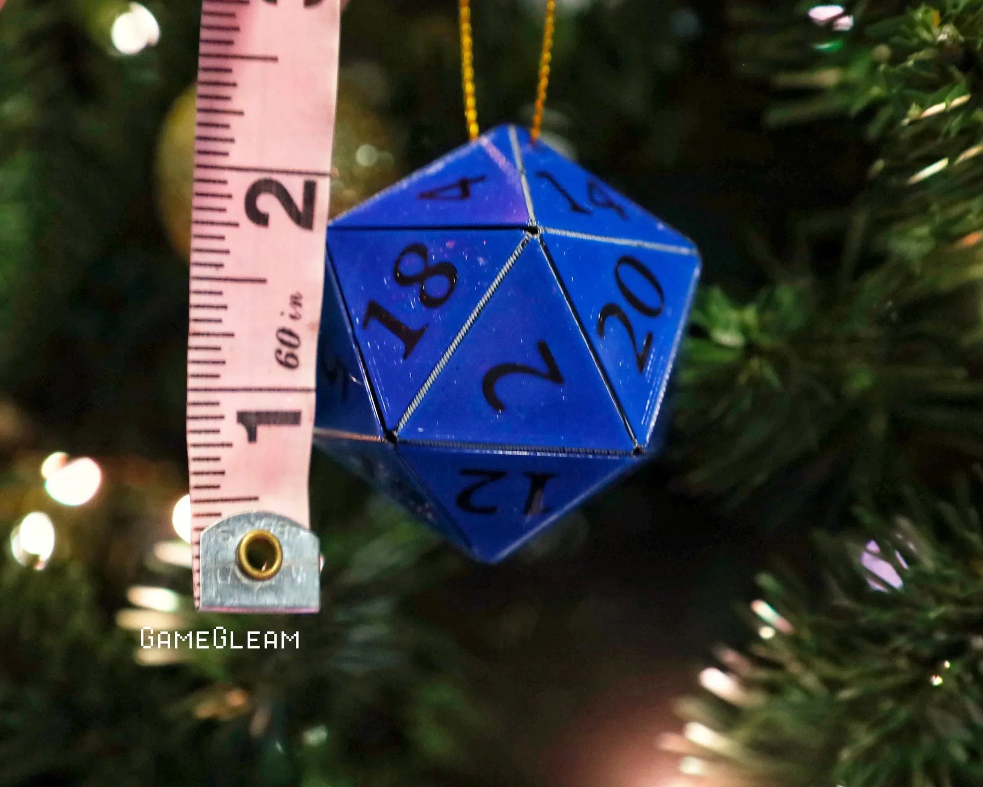 Blue 20-sided dice ornament measured with tape on a Christmas tree branch