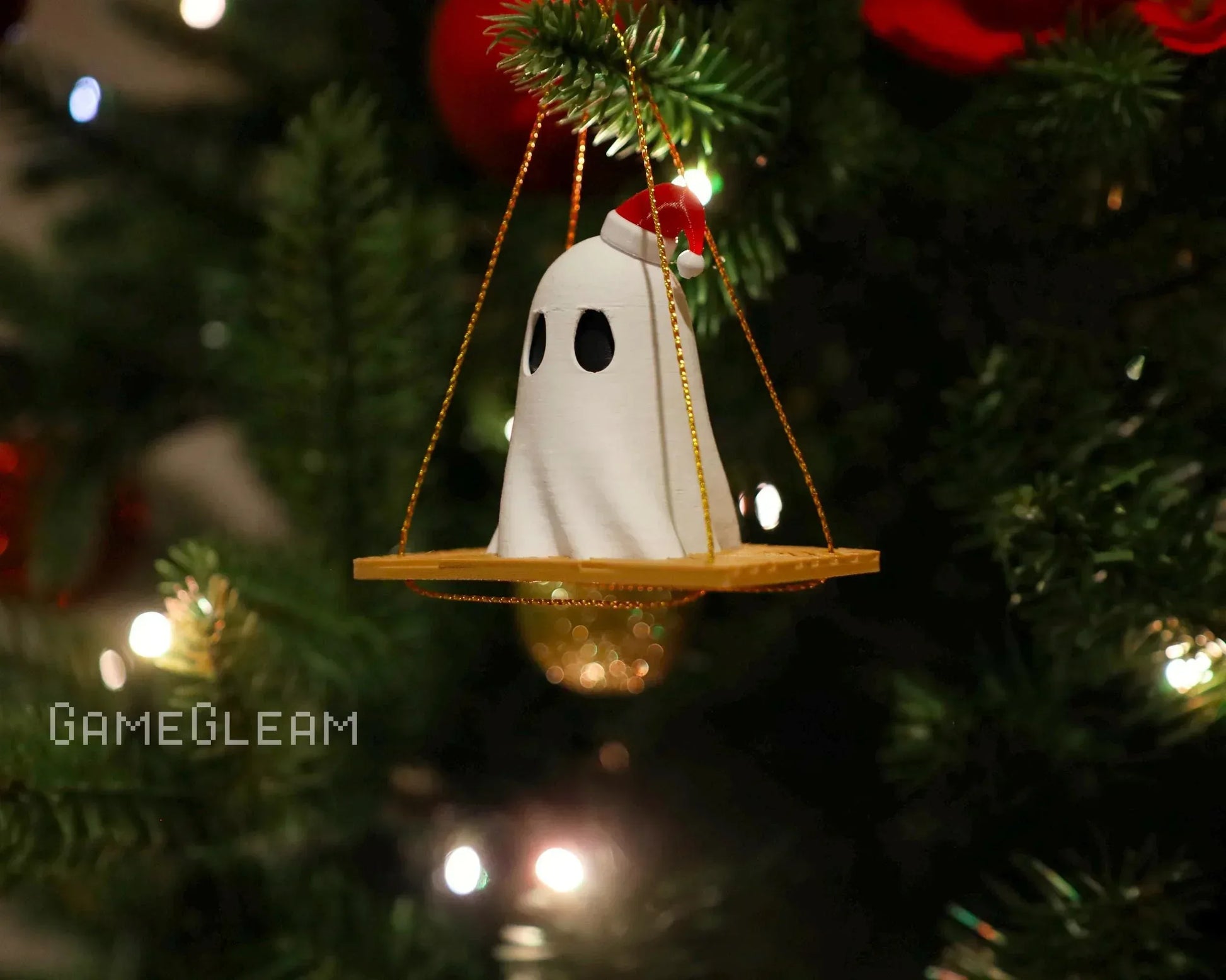 Cute ghost Christmas ornament with Santa hat on swing, hanging on a holiday tree
