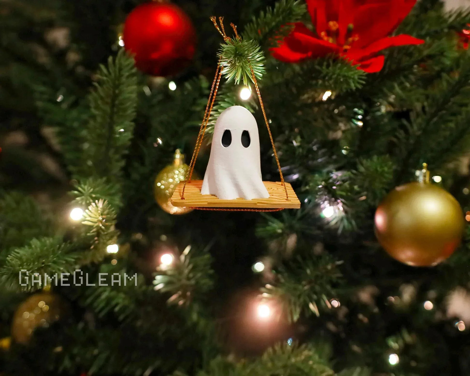 Handmade ghost ornament on swing hanging from decorated Christmas tree with lights and baubles