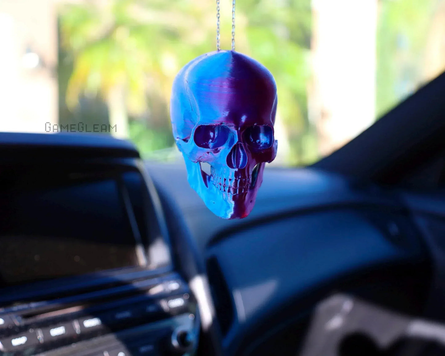 Holographic skull car charm hanging from rearview mirror in vehicle interior
