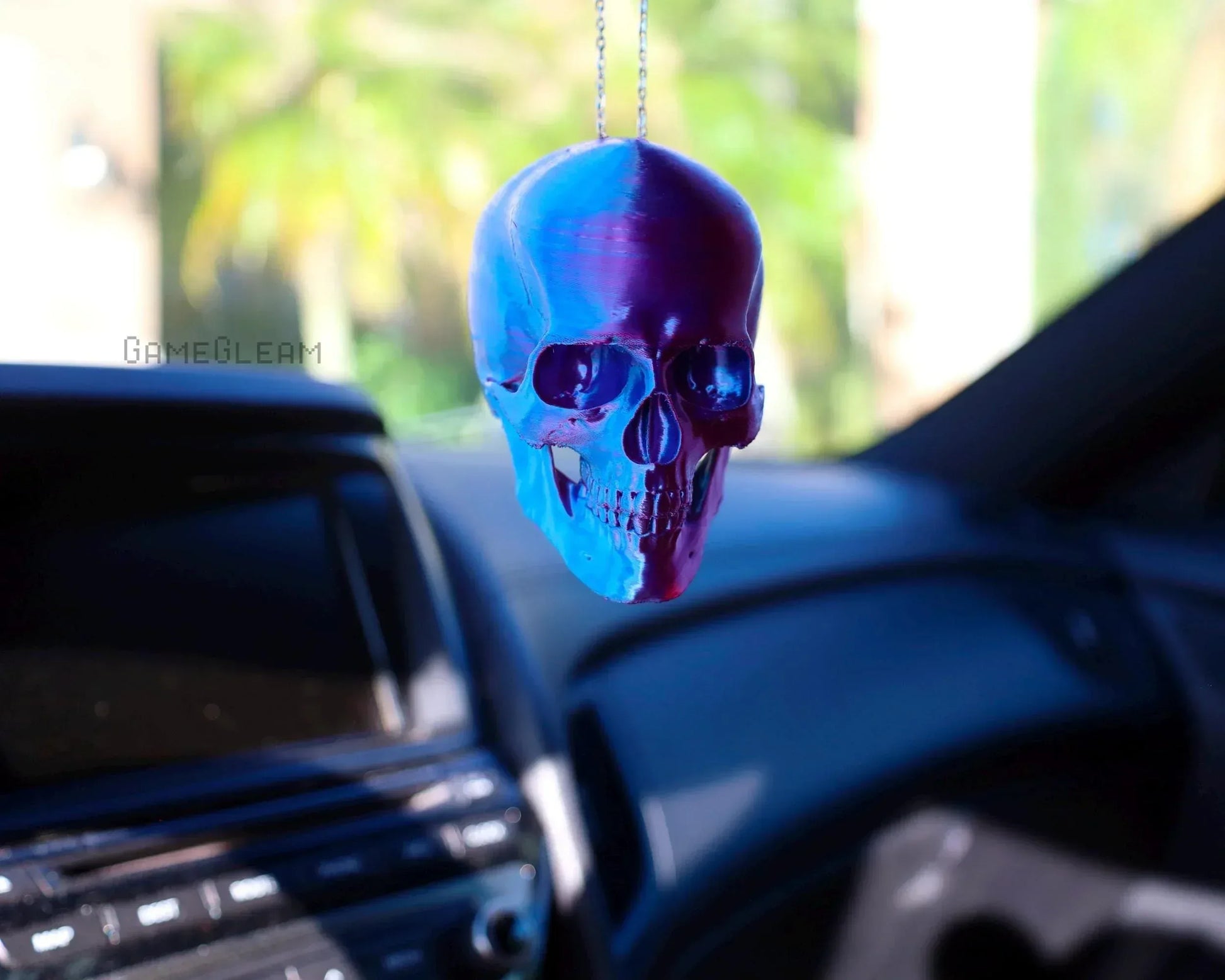 Holographic skull car charm hanging from rearview mirror in vehicle interior