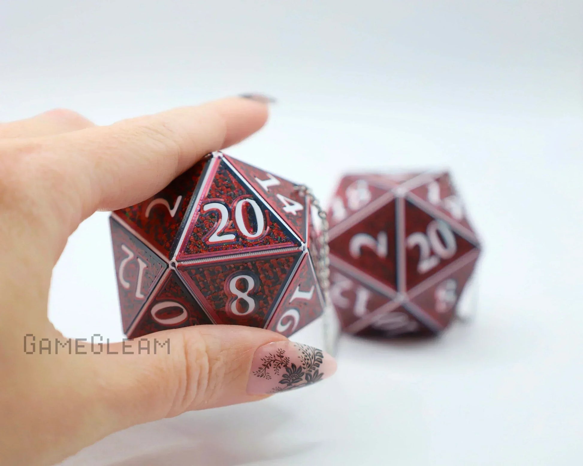 Hand holding large red 20-sided dice charm with white numbers, gamer gift accessory