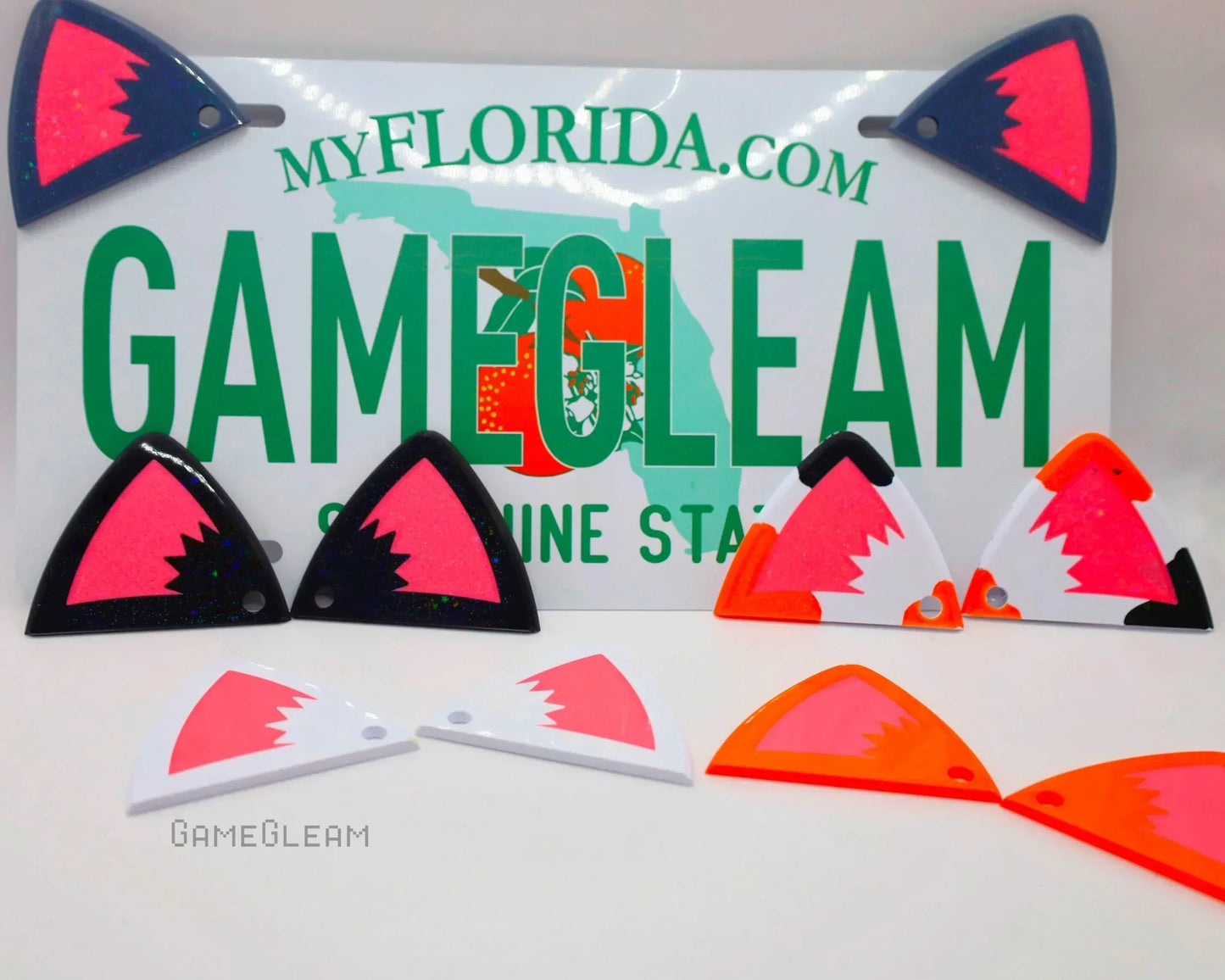 Colorful acrylic triangle charms with geometric designs arranged in front of a Florida license plate.