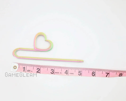 Iridescent heart-shaped car charm with a pink measuring tape on white background