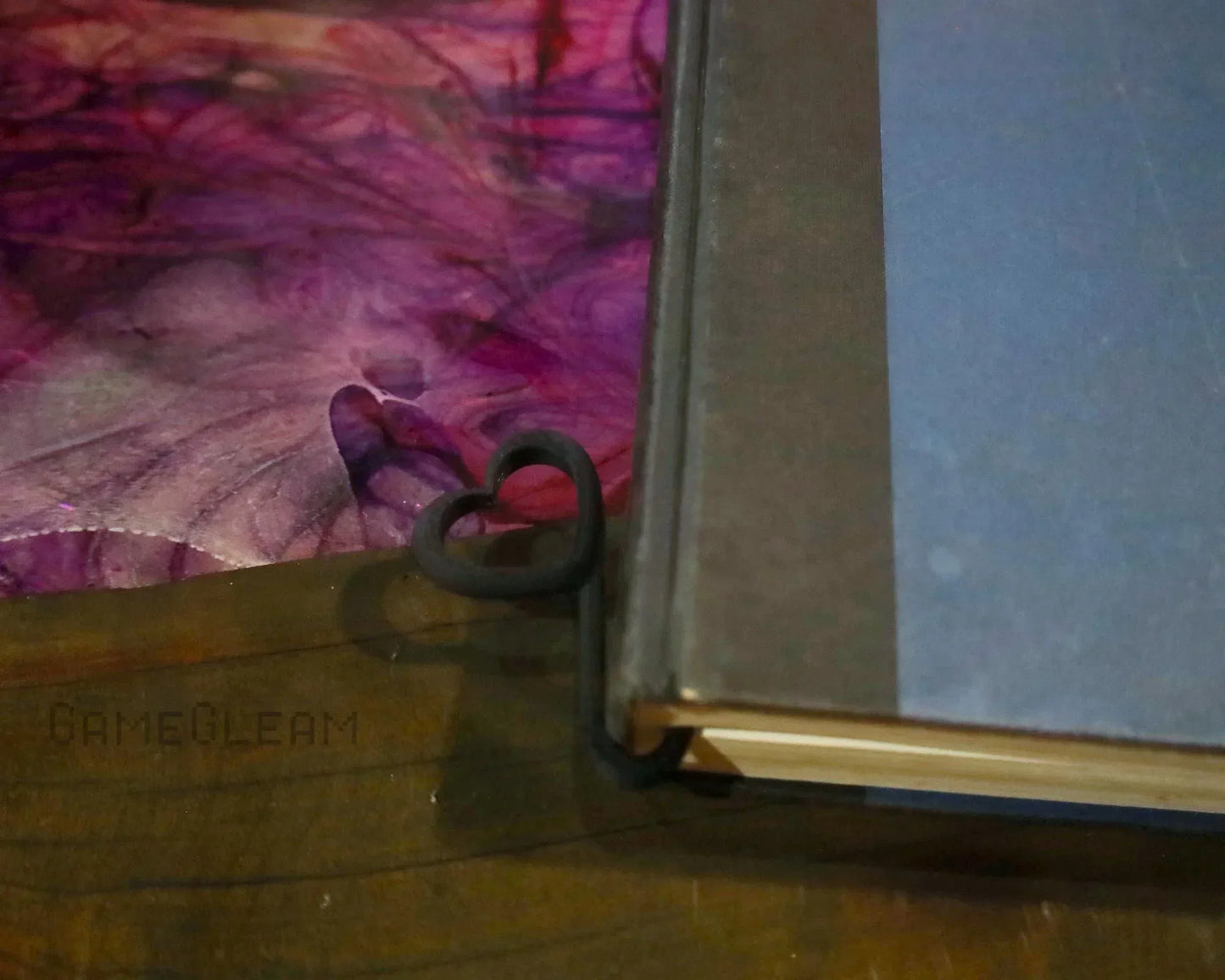 Handmade black heart-shaped metal bookmark on the corner of a closed book