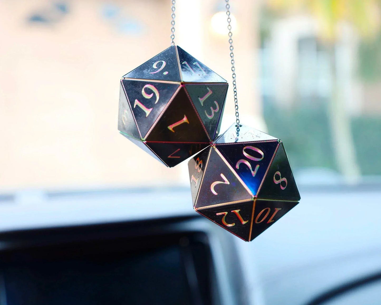 Holographic twenty-sided dice car charms hanging on a chain in a vehicle interior.
