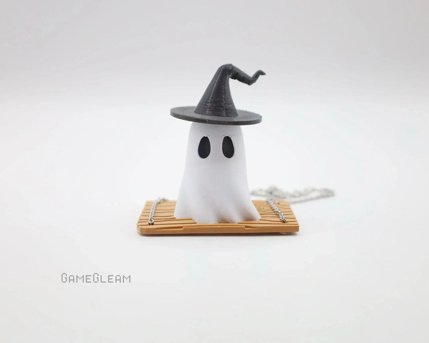 Cute ghost figurine with black witch hat, sitting on a bamboo mat, novelty gamer gift.