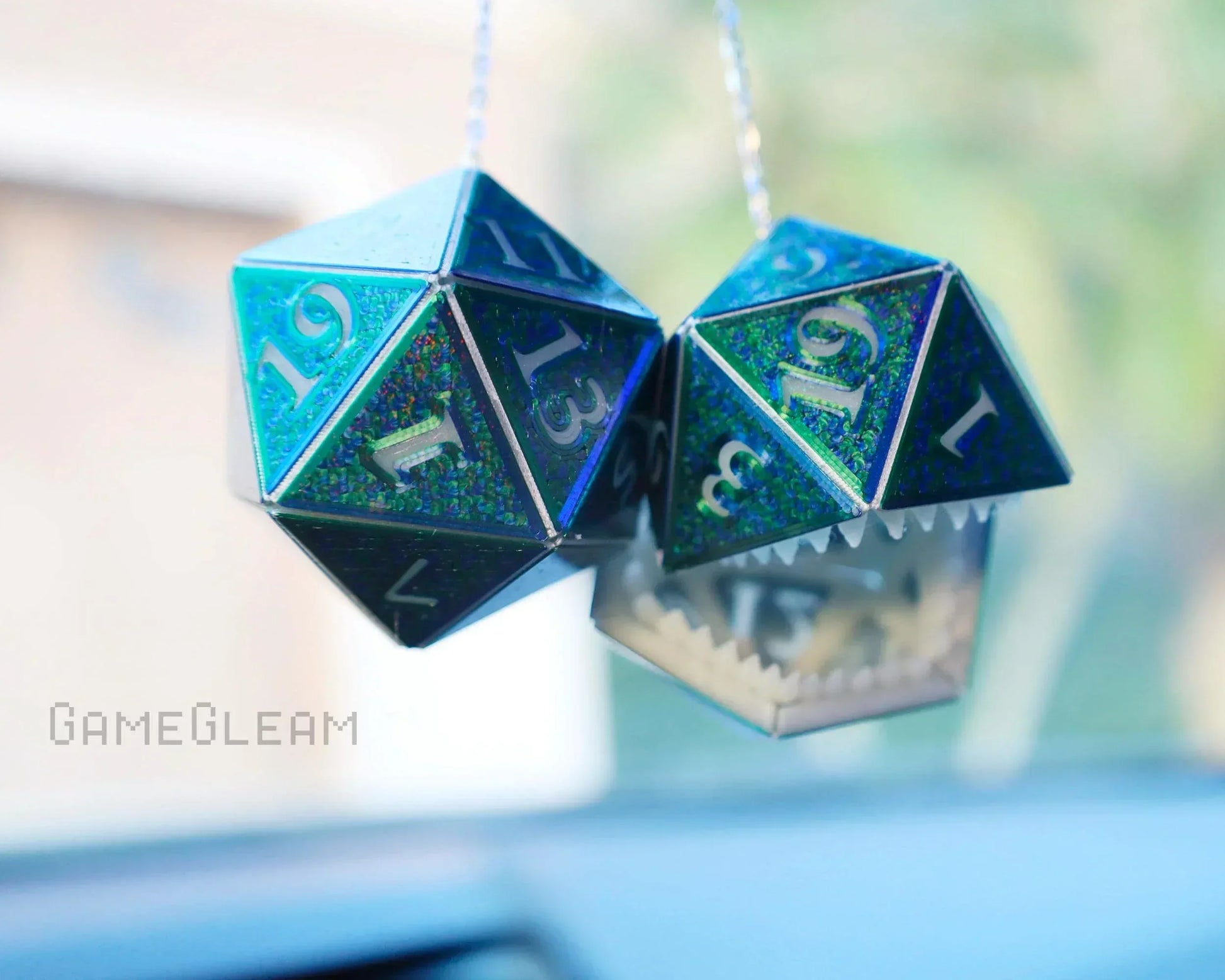 Holographic blue 20-sided dice car charm with metal teeth, hanging from rearview mirror