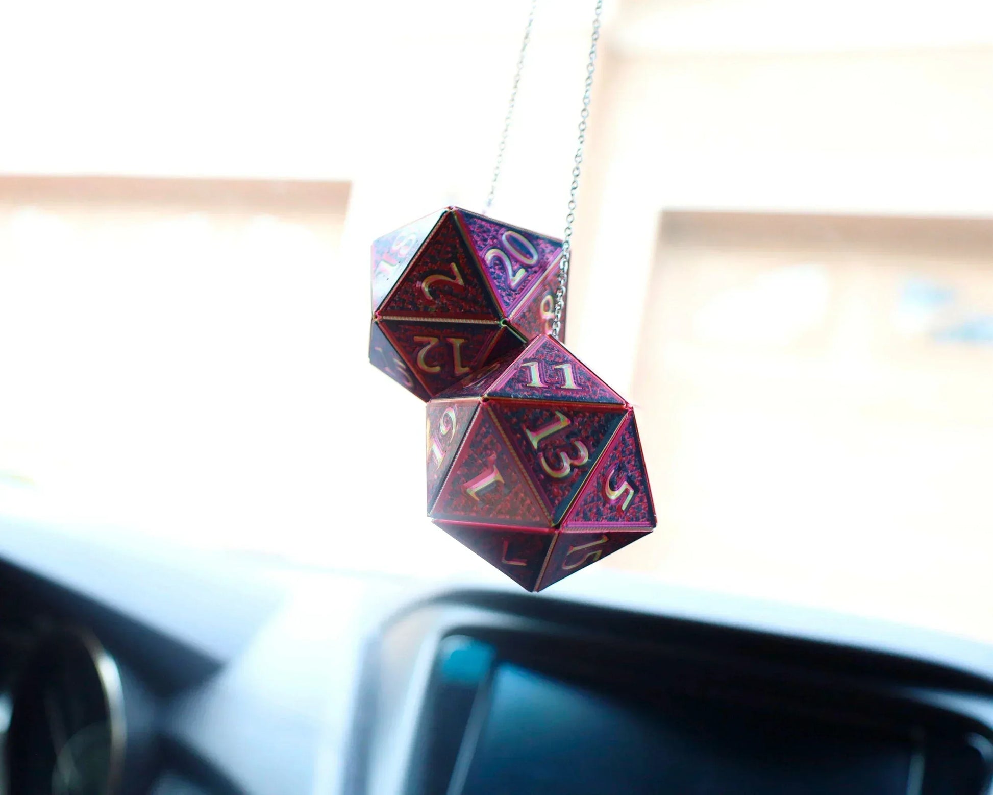 Holographic purple twenty-sided dice hanging from a car rearview mirror, gamer accessory