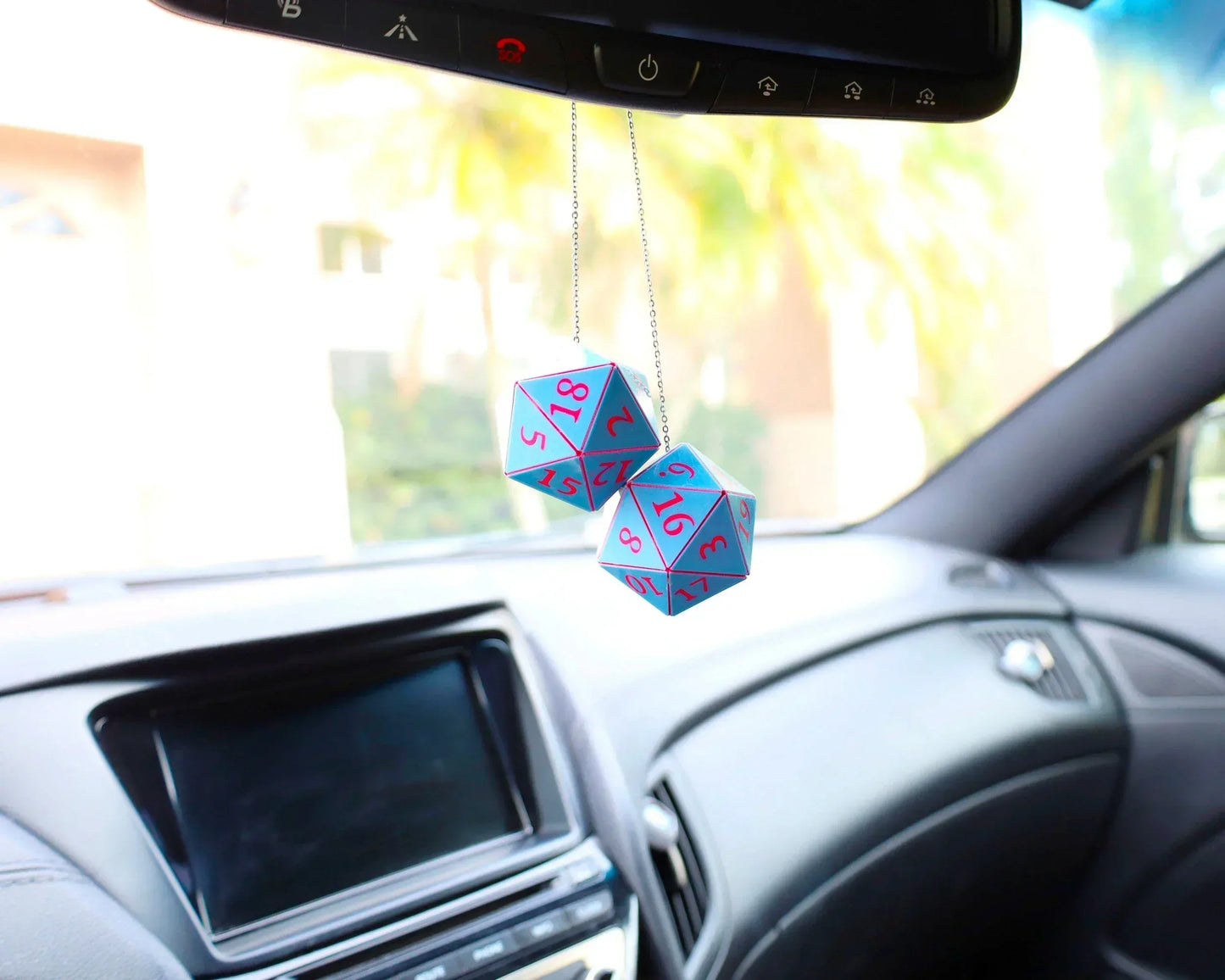 Holographic twenty-sided dice car charm with pink numbers hanging from rearview mirror in car interior