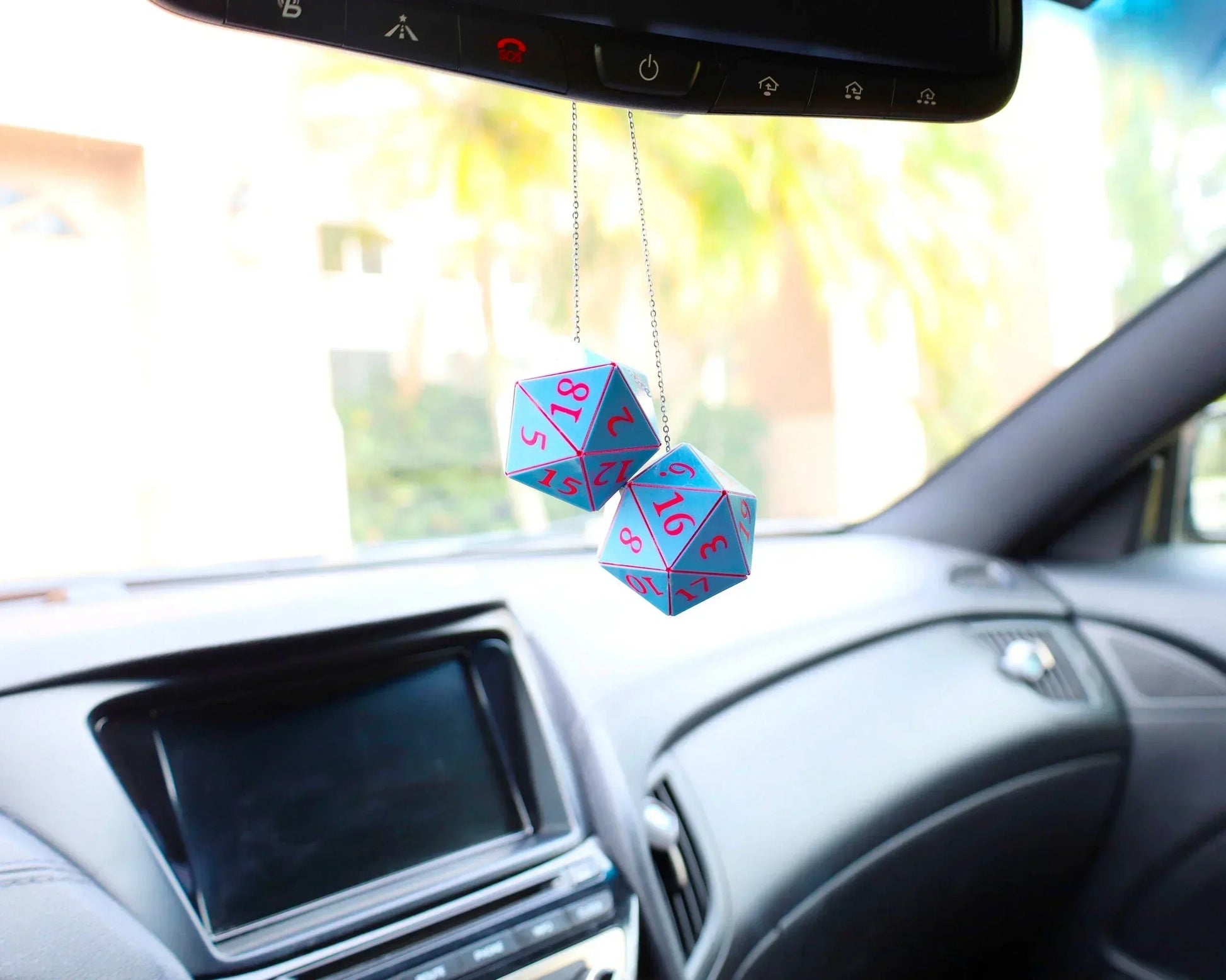 Holographic twenty-sided dice car charm with pink numbers hanging from rearview mirror in car interior