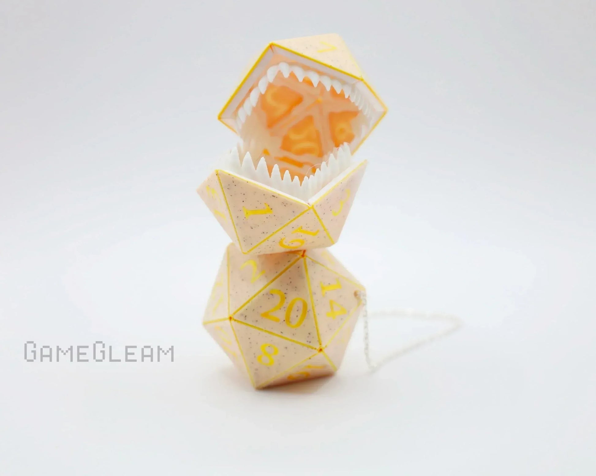 Handmade yellow D20 car dice charm with monster teeth and chain on white background