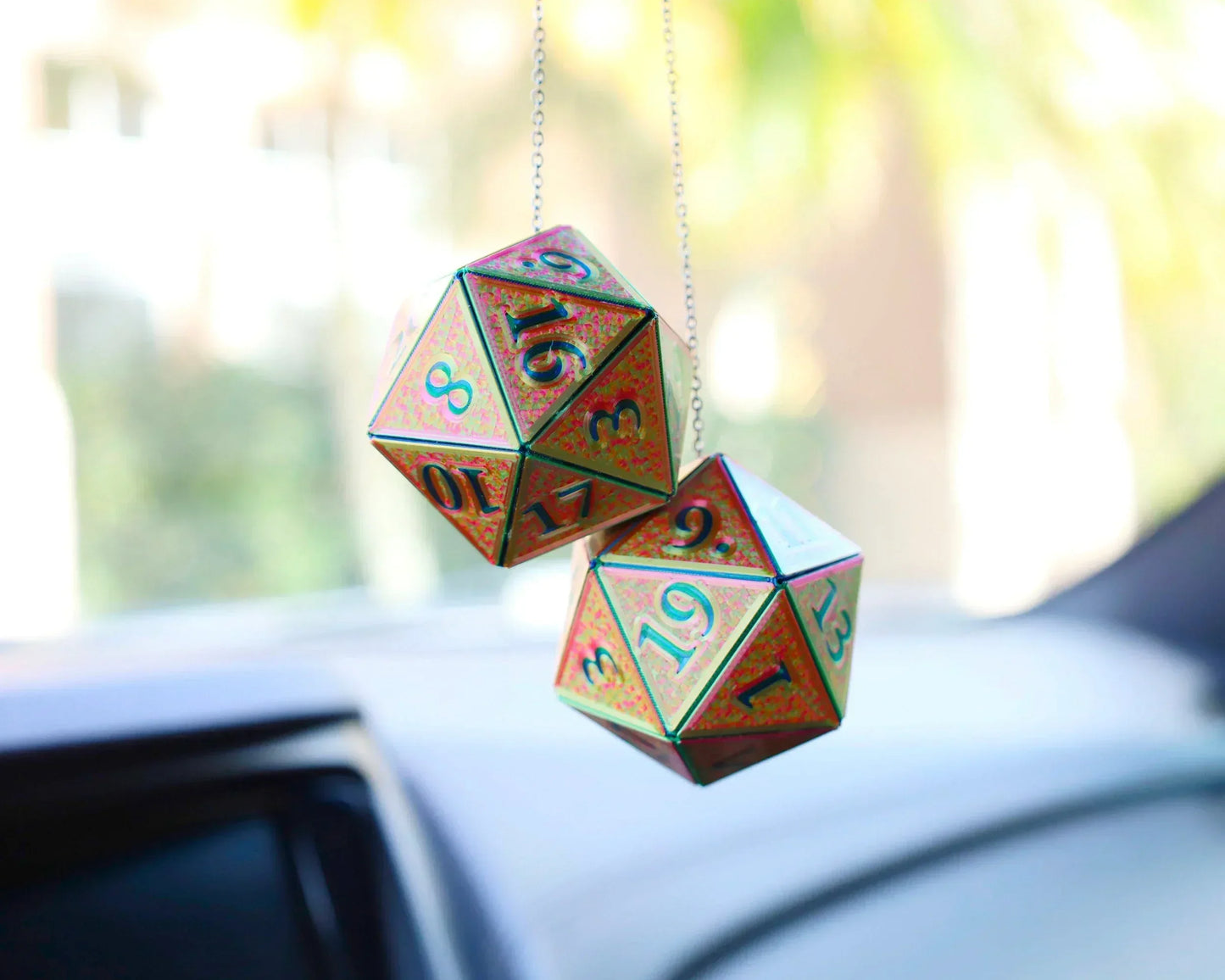 Holographic twenty-sided dice car charms hanging from a rearview mirror.