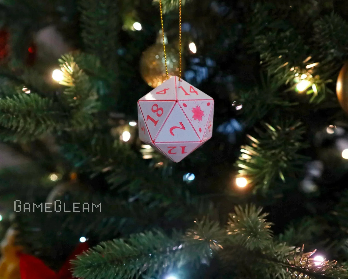Pink numbered 20-sided dice ornament hanging on a lit Christmas tree branch
