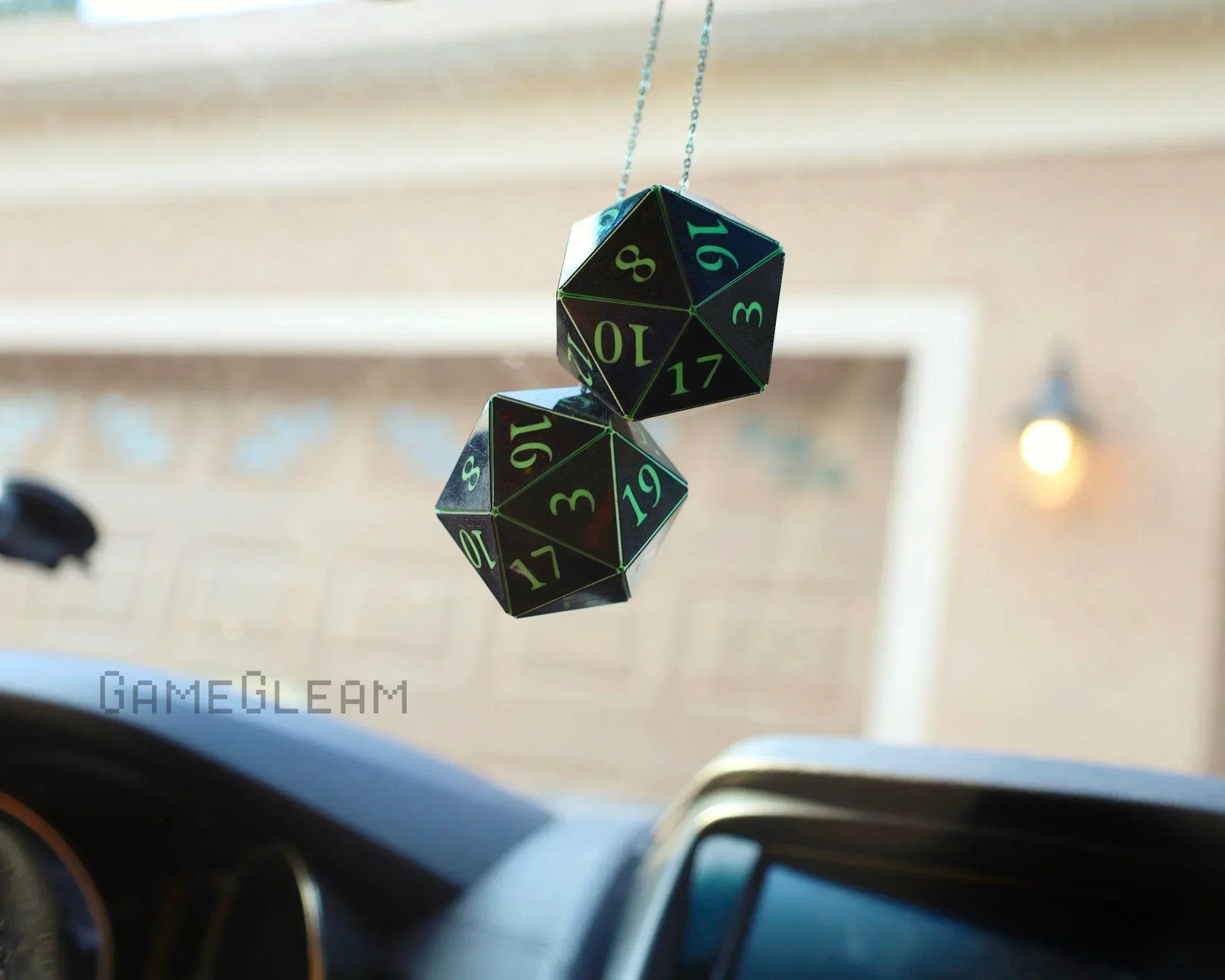 Holographic twenty-sided dice car charm hanging from rearview mirror inside a vehicle.