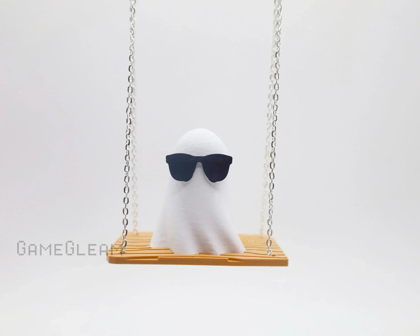 Cute ghost figurine with sunglasses sitting on a wooden swing, white background