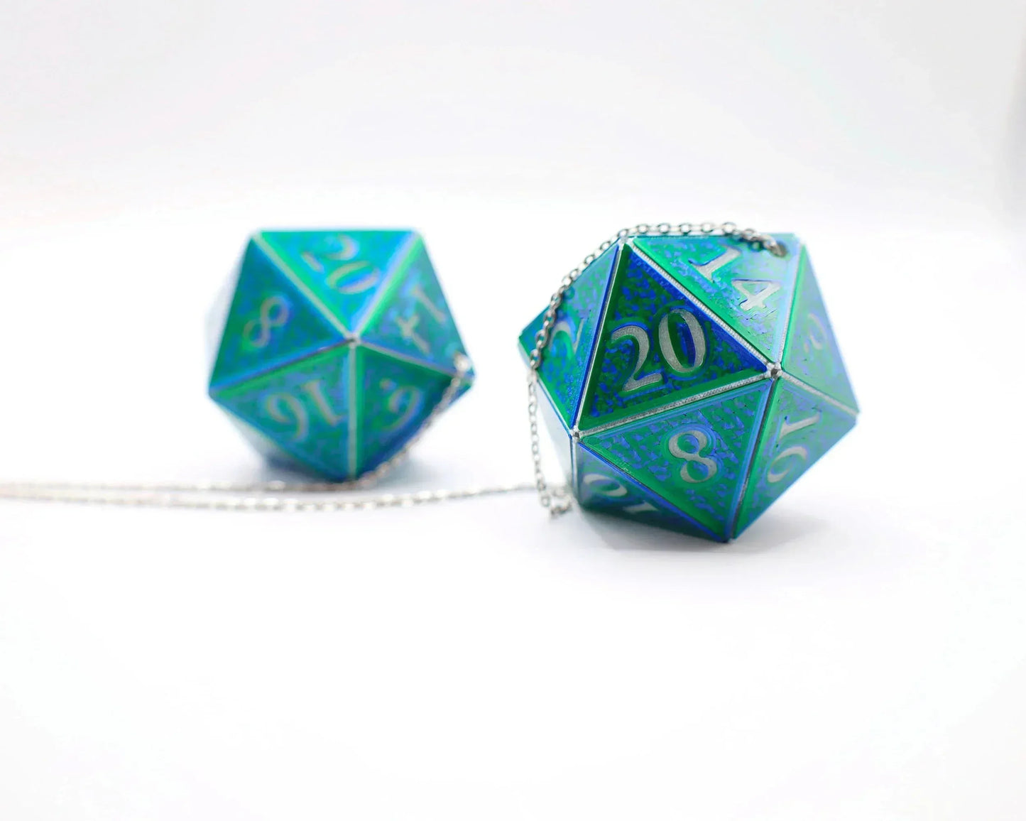 Holographic blue green twenty-sided dice car charm with silver chain on white background