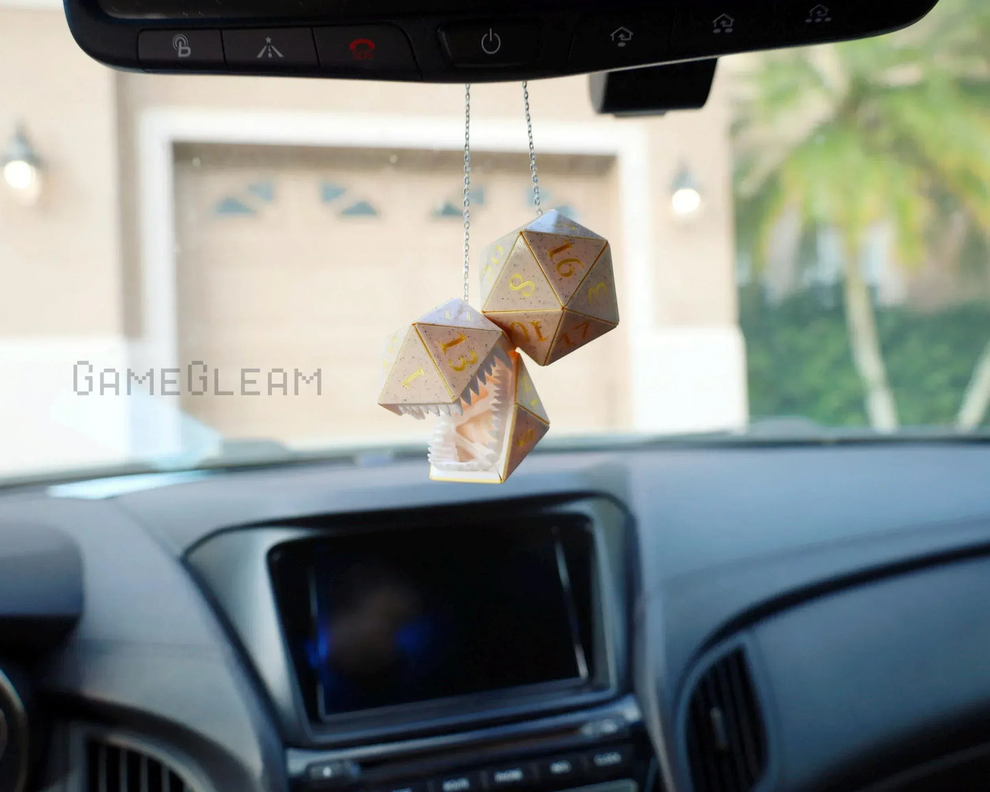 Holographic polyhedral dice car charm with monster mouth, hanging from rearview mirror