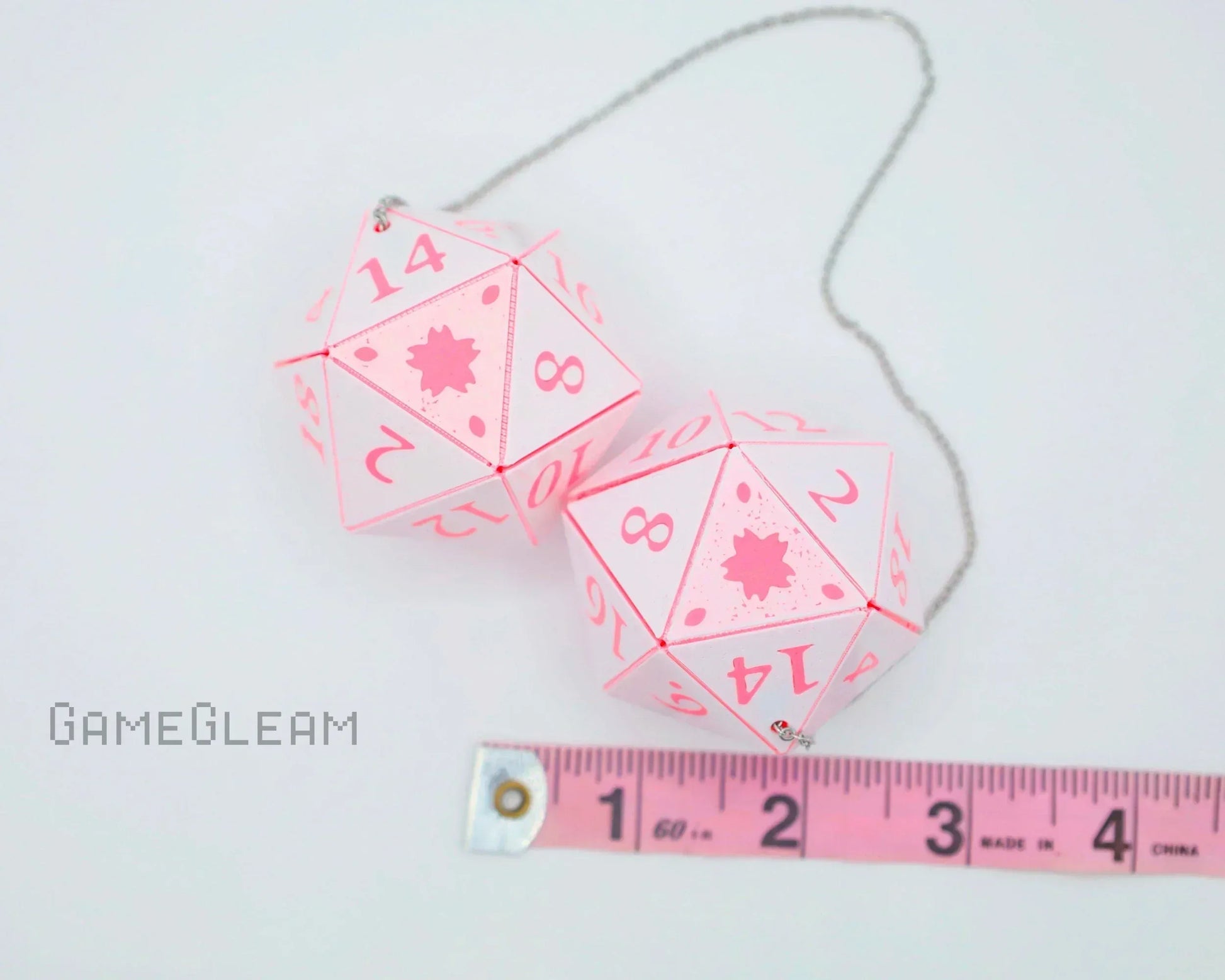 Pair of pink and white twenty-sided car dice charms with measuring tape, perfect for gamer gifts