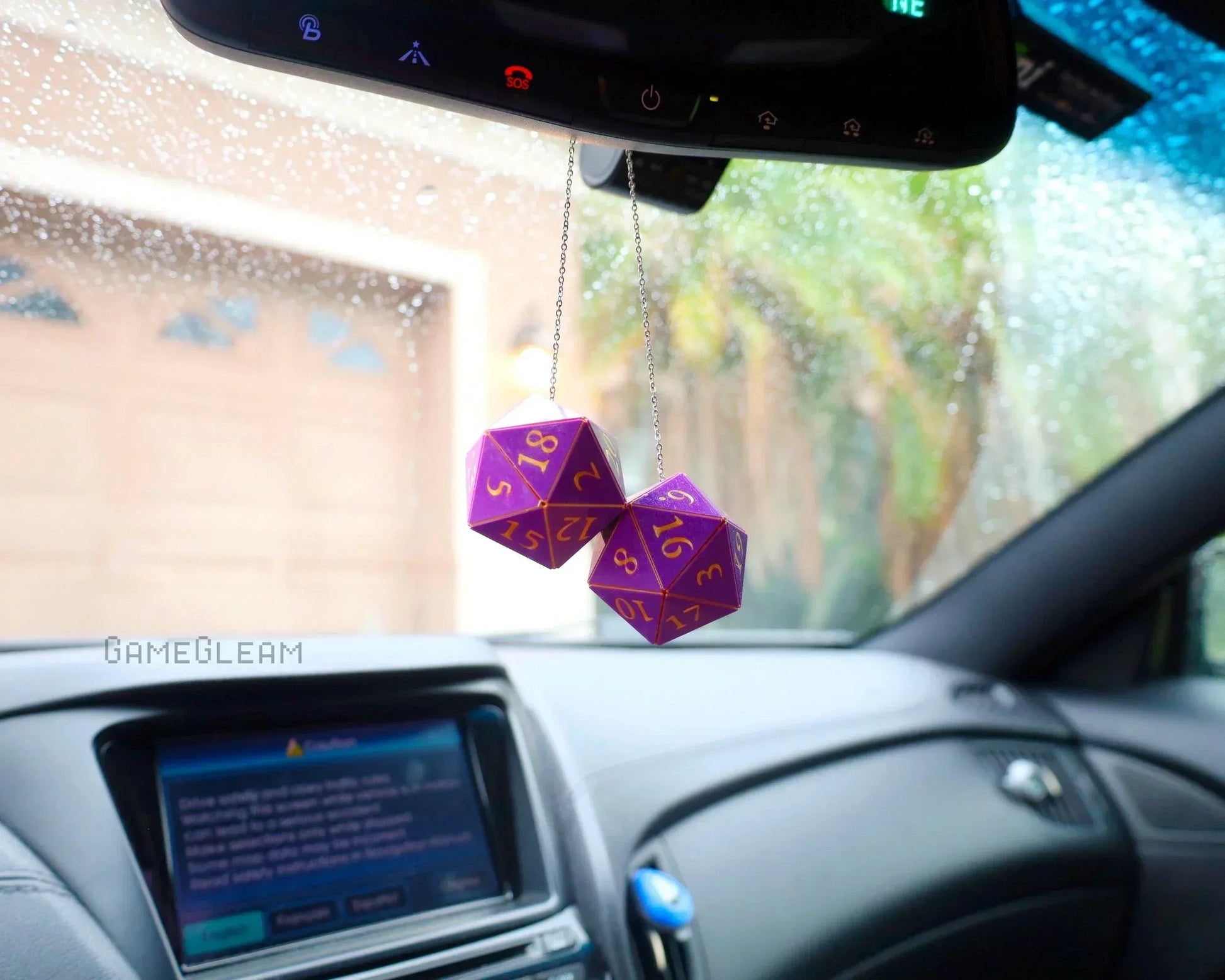 Purple twenty-sided dice car charm hanging from rearview mirror in a rainy car interior