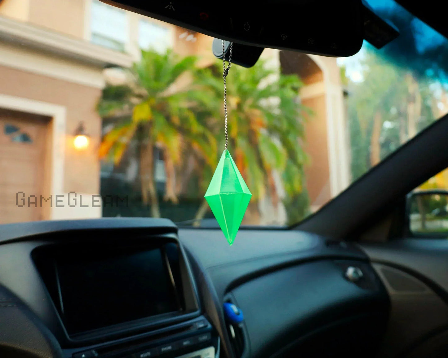 Green crystal geometric car charm hanging from rearview mirror in vehicle interior