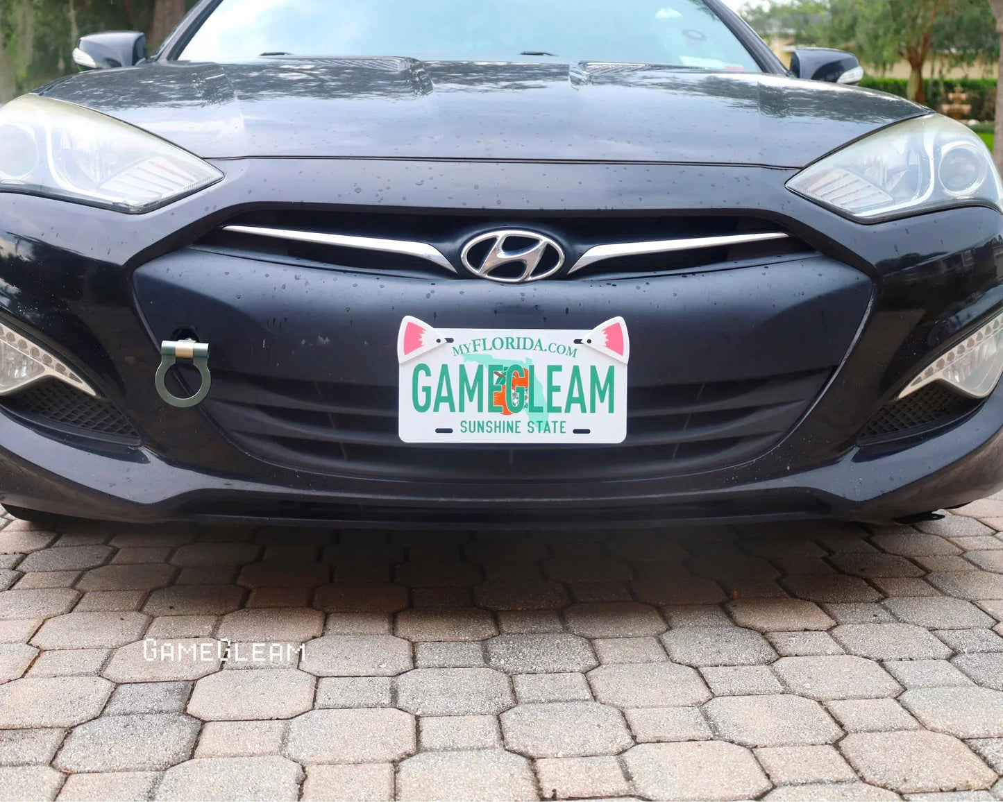 Close-up of a black Hyundai car with a custom Florida license plate and a unique tow hook accessory.
