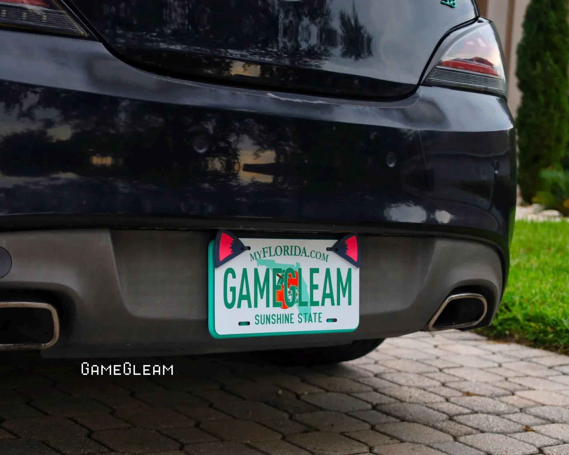 Custom Florida license plate displaying 'GameGleam' on a black car, photographed outdoors.