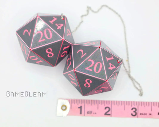 Gray and pink twenty-sided dice car charm with chain, shown next to pink ruler for size reference