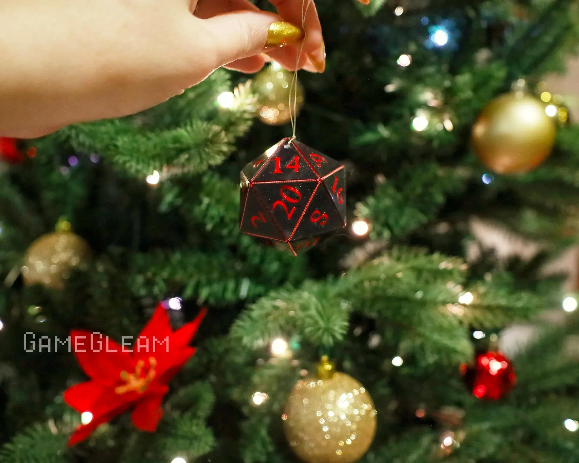 Hand holding black and red twenty-sided dice ornament on decorated Christmas tree