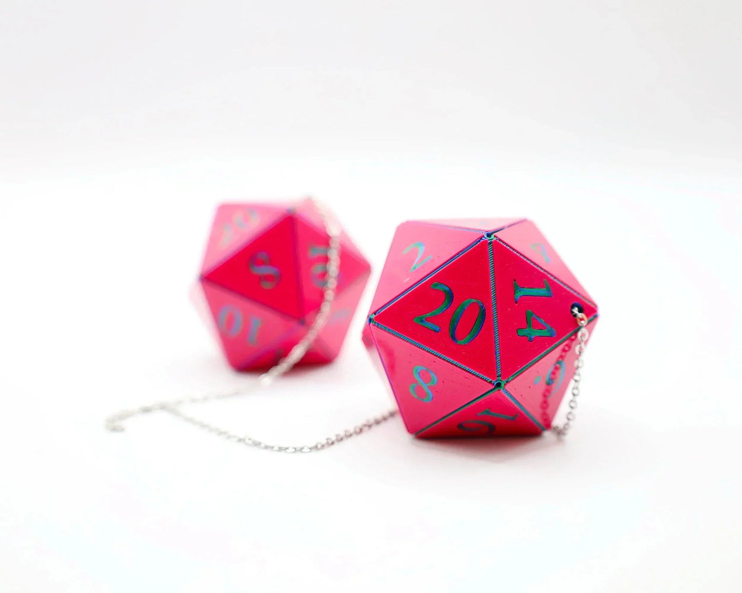Pink twenty-sided dice car charms with blue numbers and attached silver chains on white background