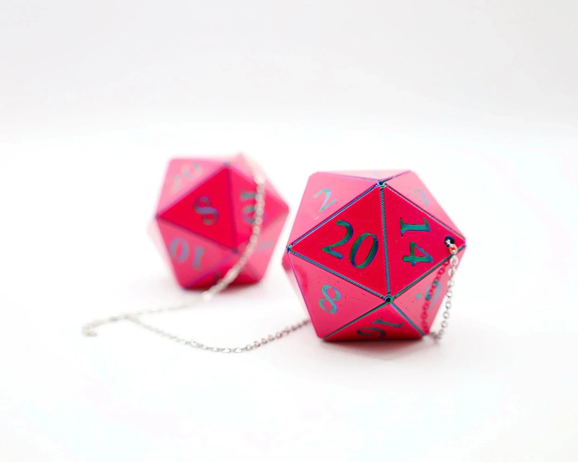 Pink twenty-sided dice car charms with blue numbers and attached silver chains on white background